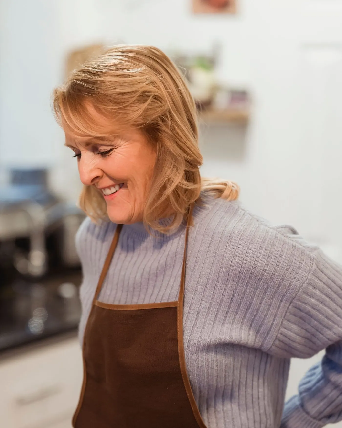 Restauratrice souriante en tablier dans sa cuisine (photo d’illustration)